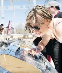  ?? DARIO AYALA/ POSTMEDIA NEWS FILES ?? Lac-Mégantic resident Katy Cloutier signs a symbolic support beam for the new Musi-Café during an event in May to mark the reconstruc­tion of the popular nightspot.