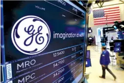  ??  ?? The GE logo appears Monday above a trading post on the floor of the New York Stock Exchange. General Electric says Jeff Immelt is stepping down as CEO and John Flannery, president and CEO of the conglomera­te’s health care unit, will take over the post...