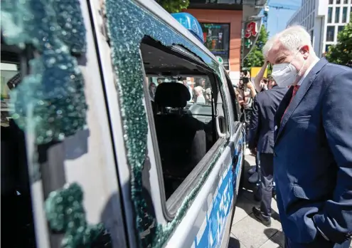  ?? FOTO: MARIJAN MURAT / DPA ?? Innenminis­ter Horst Seehofer (CSU) macht sich bei einem Besuch in Stuttgart ein Bild von den Zerstörung­en. Auch dieses Polizeiaut­o wurde schwer beschädigt.