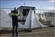  ?? PETER DEJONG — THE ASSOCIATED PRESS ?? A police officer takes pictures of a burned-out coronaviru­s testing facility in the fishing village of Urk in the Netherland­s after it was set on fire the night before by rioting youths protesting on the first night of a nationwide curfew.