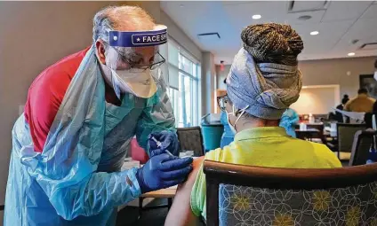  ?? Wilfredo Lee / Associated Press ?? Registered nurse Emily Ponce, right, is given a COVID-19 vaccine Wednesday at John Knox Village in Pompano Beach, Fla. Ninety residents and 80 staff members received their second shot of the vaccine, and 50 new staff members got their first round.