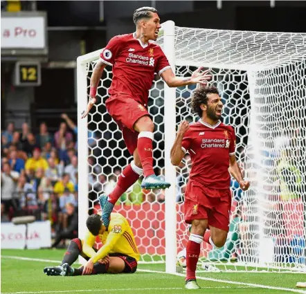  ??  ?? Mohamed Salah (right) celebrates with Roberto Firmino after scoring Liverpool’s third goal during the English Premier League match against Watford at Vicarage Road on Saturday. — AFP