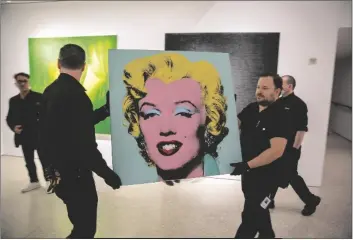  ?? TED SHAFFREY/AP ?? THE 1964 PAINTING SHOT SAGE BLUE MARILYN BY ANDY WARHOL is carried in Christie’s showroom in New York City on Sunday. The auction house predicts it will sell for $200 million on Monday, becoming the most expensive 20th-century artwork to sell at auction.