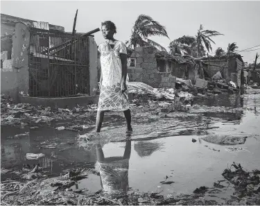  ?? Josh Estey / CARE via Associated Press ?? A woman walks through the flooded streets of Beira, Mozambique, on Sunday after Cyclone Idai made landfall. The Red Cross said 90 percent of Beira was damaged or destroyed.