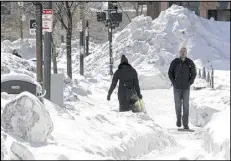  ?? AP ?? Pedestrian­s walk among mounds of snow Friday in downtown Boston. Another winter storm could bring an additional foot or more of snow to some areas.