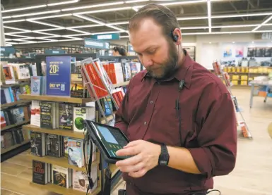  ?? Photos by Paul Chinn / The Chronicle ?? Employee Nate Emmett checks inventory using a tablet at the new Barnes & Noble bookstore in Concord.