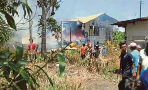  ??  ?? PENDUDUK kampung membantu selamatkan rumah mangsa yang terbakar di Kampung Hilir Sessang.
