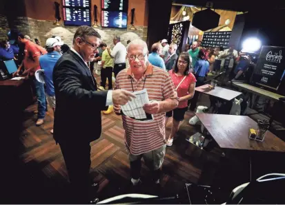  ??  ?? Gold Strike Casino employee Robert Leise, left, gives a sports betting sheet to Bill Beil of Columbia, Tennessee, during the grand opening celebratio­n of sports betting in Tunica on Wednesday. MARK WEBER/THE COMMERCIAL APPEAL