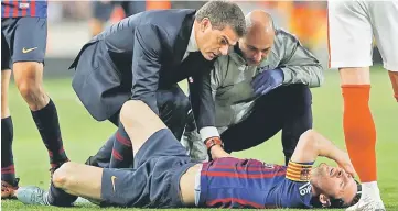  ??  ?? Barcelona’s Lionel Messi receives medical attention after sustaining an injury. — Reuters photo