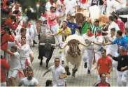  ?? Jaime Reina / AFP / Getty Images ?? Participan­ts run to stay ahead of charging bulls during the San Fermin festival in Pamplona.