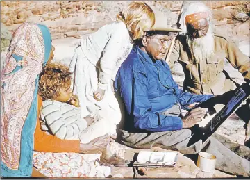  ??  ?? Photo shows family members watching Namatjira sitting on a rock as he paints. — Reuters photo