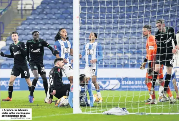  ?? George Wood/Getty Images ?? Argyle’s Joe Edwards slides in the winning goal at Huddersfie­ld Town