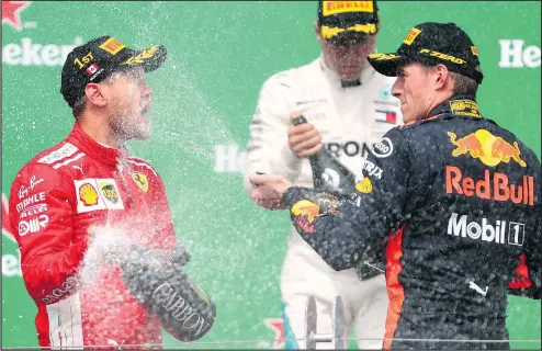  ?? Winner Sebastian Vettel of Ferrari is doused with champagne on the podium by third-place finisher Max Verstappen of Red Bull Racing as they celebrate their success at the Canadian Grand Prix in Montreal yesterday. Dan Istitene/Getty Images ??