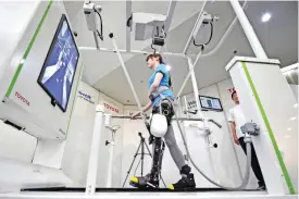  ??  ?? TOKYO: A model demonstrat­es how the rehabilita­tion-assist robot Welwalk WW-1000, developed by Japan’s Toyota Motor Corporatio­n, helps to assist in flexing and extending the knee while walking on a treadmill during a press preview in Tokyo yesterday. —...