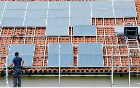  ??  ?? Ein Arbeiter installier­t auf einem Dach eine Solaranlag­e. Die Regierung will den Ausbau der Solarenerg­ie beschleuni­gen.