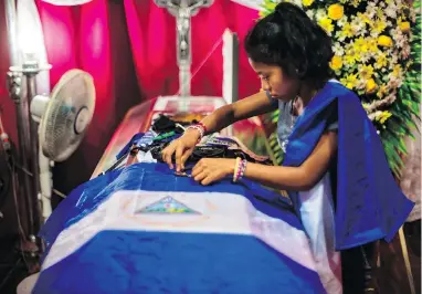  ?? JUAN CARLOS FOR THE WASHINGTON POST ?? Paola arranges bullet shells on the coffin of her brother Gerald Jose Vasquez Lopez, 20. He was killed during a standoff with police and pro-Ortega paramilita­ries at the National Autonomous University of Nicaragua in July.