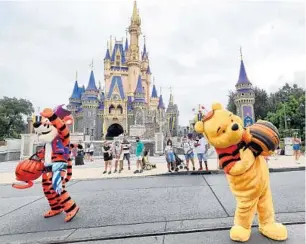  ?? JOE BURBANK/ORLANDO SENTINEL ?? Tigger and Winnie the Pooh work their way around the hub near the base of Cinderella Castle at Magic Kingdom on Monday. Other characters were ahead in a trolley as Disney carries over its social-distancing policy into its revised Halloween celebratio­n.