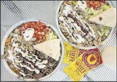  ??  ?? Beef Gyro Platter (left) and Chicken Platter (right) with toppings, special white sauce, and hot sauce at the Halal Guys.