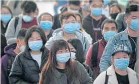  ?? /AFP ?? Brave face: Passengers wearing face masks arrive at Changsha railway station in Changsha. China cancelled all outbound group tours in late January, as it aggressive­ly seeks to contain the virus.