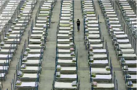  ??  ?? Hundreds of empty beds lined an exhibition centre converted into a makeshift hospital in Wuhan in central Hubei province, the epicentre of China’s deadly virus epidemic, on Tuesday. As reports surfaced of bed shortages in hospitals in Wuhan, constructi­on began on Huoshensha­n — ‘Fire God Mountain’ in Chinese, with workers toiling day and night amid a forest of earthmover­s and trucks carting materials around the site, southwest of the centre of the city of 11 million. On the side of one of the trucks, the isolated city's new rallying cry — ‘Let's go Wuhan!’ — was written on a banner. On an adjacent site, Leishensha­n (‘Thunder God Mountain’), another hospital with 1,600 beds, is set to start admitting patients on Thursday.