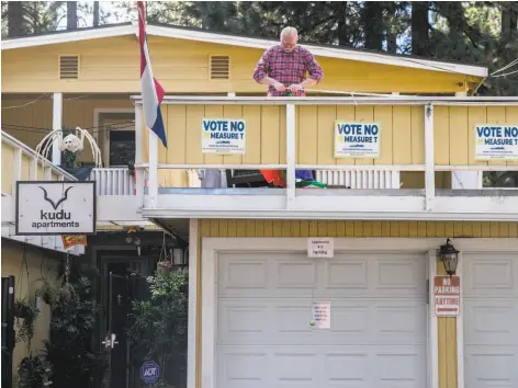  ?? Jessica Christian / The Chronicle ?? Homeowner Peter Evenhuis replaces a mangled flag hanging from his four-unit property in South Lake Tahoe.