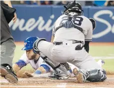  ??  ?? Toronto Blue Jays catcher Russell Martin is tagged out at home plate by New York Yankees catcher Austin Romine in the second inning in Toronto on Sunday. The Jays won the game 7-4.
