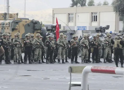  ??  ?? Turkish and Iraqi soldiers carry their national flags in a ceromony to hand over the border gate.