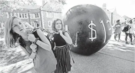  ?? PAUL J. RICHARDS/AFP/GETTY IMAGES ?? Students at Washington University in St. Louis pull a mock “ball and chain” representi­ng outstandin­g student debt. The figure recently hit $1.5 billion.