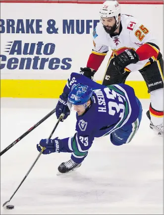  ?? GERRY KAHRMANN/PNG ?? Canucks captain Henrik Sedin gains control of the puck after being hit by Flames winger Brandon Bollig in the first period on Saturday night.