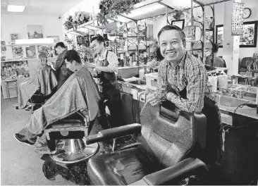  ?? [PHOTOS BY JIM BECKEL, THE OKLAHOMAN] ?? Ky Nguyen, right, owns the family business, Hank’s Barber Shop, where he and his sons, Dieu Thy Nguyen, standing middle, and Anh Thy Nguyen give haircuts to customers on Tuesday.