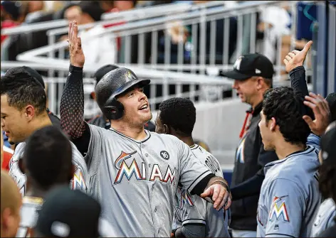  ?? JOHN BAZEMORE / AP ?? Marlins first baseman Justin Bour celebrates in the dugout after hitting a solo homer Friday against the Braves. Bour finished 1 for 3 with a walk to raise his average to .295 and his slugging percentage to .601.