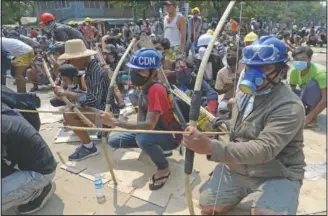  ??  ?? Anti-coup protesters prepare makeshift bow and arrows March 27 to confront police in Thaketa township.