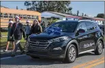  ??  ?? Stanton Collemer and other members of the Cancer Alliance walk to the Montez family home next to the Hyundai Tucson being presented to them.