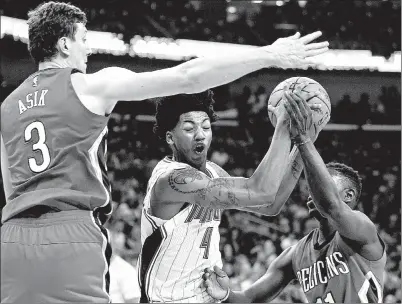  ??  ?? ABOVE: Orlando Magic guard Elfrid Payton drives to the basket between New Orleans Pelicans center Omer Asik, left, and guard Jrue Holiday during the first half Tuesday in New
Orleans.