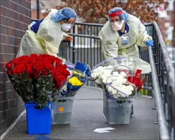  ?? Kathy Willens/Associated Press ?? Emergency room nurses transport buckets of donated flowers up a ramp outside Elmhurst Hospital Center’s emergency room Saturday in New York. The hospital has been heavily taxed by treating an influx of coronaviru­s patients during the current viral pandemic.