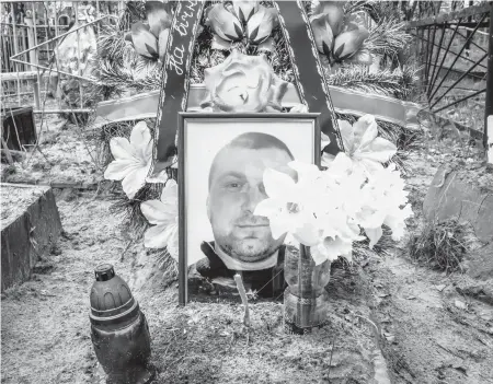  ?? DANIEL BEREHULAK/THE NEW YORK TIMES PHOTOS ?? A photo of Oleh Abramova, who was executed by Russian forces March 5, adorns his grave in Bucha, Ukraine.