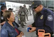  ??  ?? A Customs and Border Protection officer speaks with a Cuban asylum seeker as newly arrived U.S. Army troops observe at the bridge with Mexico.