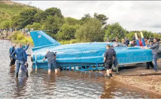  ?? David Cheskin / Associated Press ?? The restored jet boat is put into the water for the first time in more than 50 years off the Isle of Bute on the west coast of Scotland. It will initially undergo low-speed tests.