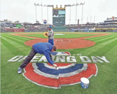  ?? JOHN SLEEZER/AP ?? Royals grounds crew manager Evan Fowler paints the opening-day logo behind home plate on Wednesday. The Royals open the baseball season Thursday against the White Sox.