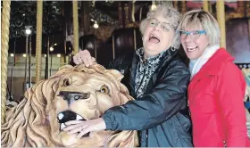  ?? ALLAN BENNER THE ST. CATHARINES STANDARD ?? Donna Duffy, left, whose grandfathe­r once owned the historic Lakeside Park Carousel, pretends she’s being attacked by the lion on the ride, with Friends of the Carousel secretary Katherine Nelson-Riley.