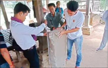  ?? SUPPLIED ?? Officials inspect a stone tablet found in Anlong Veng on Friday that bears inscriptio­ns of an unknown Khmer king’s royal directive.