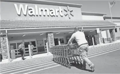  ?? JOE RAEDLE, GETTY IMAGES ?? Walmart employee Yurdin Velazquez returns grocery carts to a store in Miami. Walmart is the largest grocery retailer in the United States and is more than three times bigger than Amazon, based on revenue.