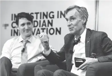  ?? JUSTIN TANG / THE CANADIAN PRESS ?? Bill Nye shows off a Canadian $5 bill, which features an astronaut and the Canadarm as Prime Minister Justin Trudeau looks on during an armchair discussion highlighti­ng Canadian innovation at the University of Ottawa on Tuesday.