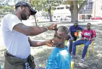  ??  ?? Nsimba Narvito Bkum, 13, of Angola, gets a trim Monday from Pacho Bolongi Bonkino, 33, of the Democratic Republic of the Congo. The group was headed to Maine after seeking asylum.