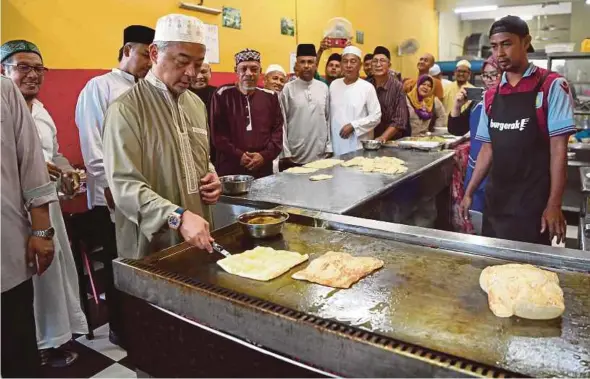  ?? BERNAMA PIC ?? Sultan of Pahang Sultan Abdullah Sultan Ahmad Shah making roti canai at a restaurant in Kuantan yesterday.