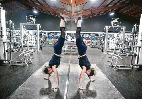  ?? Photos by Michael Ciaglo / Staff photograph­er ?? Fox 26 reporter Ivory Hecker does a handstand walk as she works out at Alphalete Gym.