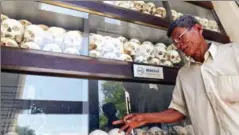  ?? TANG CHHIN SOTHY/AFP ?? A man looks at victims’ skulls killed by the Khmer Rouge regime at the Choeung Ek killing field memorial in Phnom Penh.