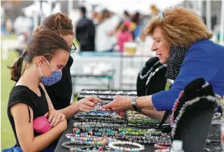  ?? Photos by Jason Fochtman / Staff photograph­er ?? Sue Vogt shows Grace White and Brianna Robichaus beads her husband made by hand during Arts in the Park at Northshore Park in The Woodlands on March 13.