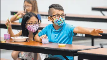  ?? Chris Day Las Vegas Review-Journal file ?? Ellura H., 8, and Giani B., 8, mix paints in the cafeteria as Giani reaches toward another camper during a summer camp July 16, 2020, at Legacy Traditiona­l School.