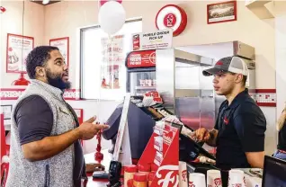  ?? NICK GRAHAM / STAFF ?? Chace Baxter takes the first order from Terrell Cooper at Freddy’s Frozen Custard and Steakburge­rs on opening day Tuesday in Fairfield.